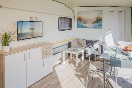 a living room with a tv and a table and chairs at TiBu - Mietwohnwagen Fehmarn in Fehmarn