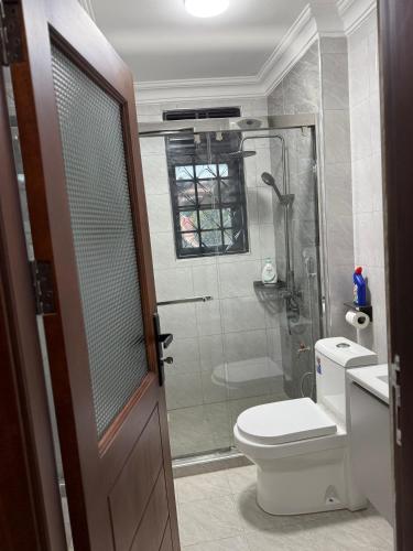 a bathroom with a shower and a toilet and a glass door at Mirembe housing in Nalakonge