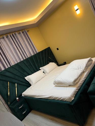 a bedroom with a large bed with a green headboard at Mirembe housing in Nalakonge