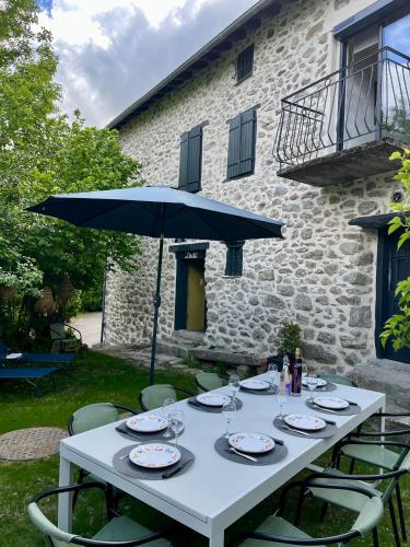 une table blanche avec un parasol bleu et des chaises dans l'établissement Les cimes de l'Oustal, à Ax-les-Thermes