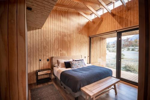 a bedroom with a bed and a large window at Refugios Australes - Cerro Castillo - Carretera Austral - Patagonia in Villa Cerro Castillo