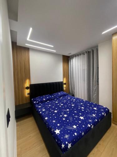 a bedroom with a bed with a blue blanket at Klindi Apartaments in Pogradec
