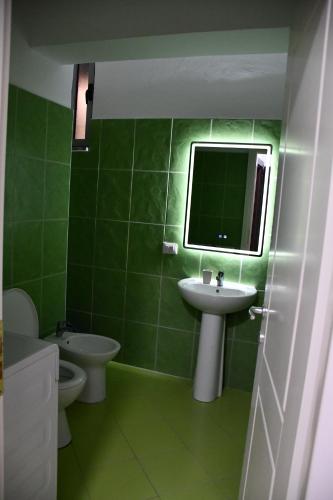 a green bathroom with a sink and a mirror at Apartament Niko Shengjin 1 in Shëngjin