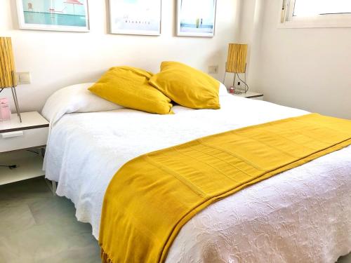 a bed with yellow sheets and two pillows on it at Playa Serena 2 habitaciones PRIMERA LINEA DE PLAYA Vista al Mar in Roquetas de Mar