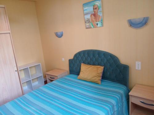 a small bedroom with a bed with a blue headboard at Maison indépendante agréable et ensoleillée in La Celle-sous-Gouzon