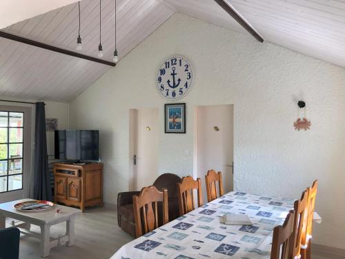 une salle à manger avec une table et une horloge au mur dans l'établissement Le Tilburg, à Grandcamp-Maisy