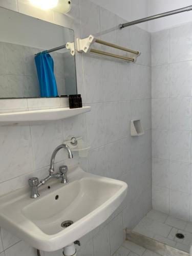 a white bathroom with a sink and a mirror at Captain Stavros in Pollonia