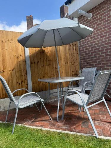 a table and chairs and an umbrella on a patio at Modern Family 3 bedroom house,Free Parking,Garden in Dagenham