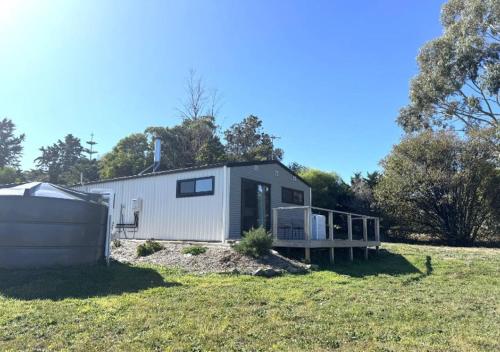 a small house in a field next to a field at studio one bay view in Nubeena