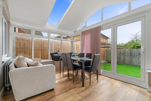 a dining room with a table and chairs and windows at 3 Bed - Sleeps 7 - Hot-Tub - Free Parking in Hornchurch