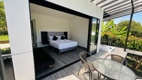 a bedroom with a bed and a balcony with tables and chairs at Luxe Glamping in Moniquirá