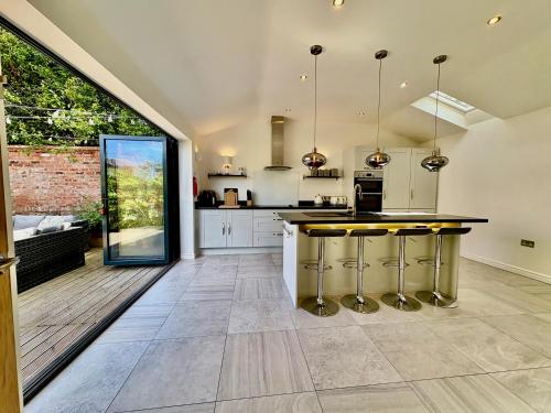 an open kitchen with a counter with stools at Eden Cottage in Frodsham
