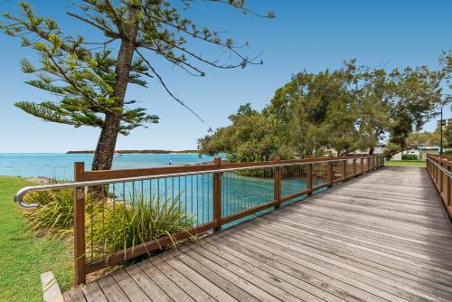 a wooden boardwalk over the water with a tree at Sails Resort Caloundra in Golden Beach