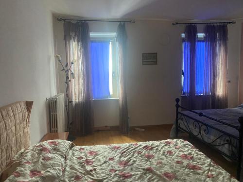 a bedroom with a bed and two windows with curtains at biancaneve i suoi nani in Asti