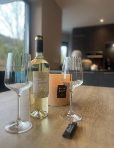 a bottle of wine and two wine glasses on a table at Auszeit am Murmelbachtal - Ruheoase mit Stellplatz in Wuppertal