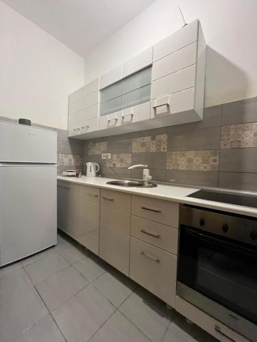 a kitchen with white cabinets and a sink and a refrigerator at Apartman Aida in Jablanica