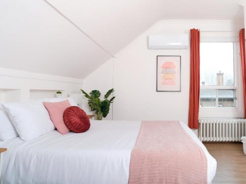 a bedroom with a white bed with pink pillows at BALCON BLANC - Auberge à Chicoutimi, Saguenay in Saguenay