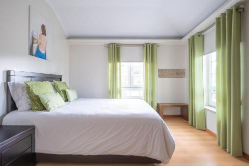 a bedroom with a large bed with green curtains at Casa do Sino, Estadia Moderna Perto do Douro in Tarouca