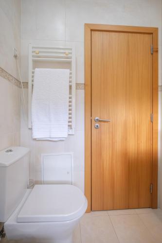 a bathroom with a toilet and a wooden door at Casa do Sino, Estadia Moderna Perto do Douro in Tarouca