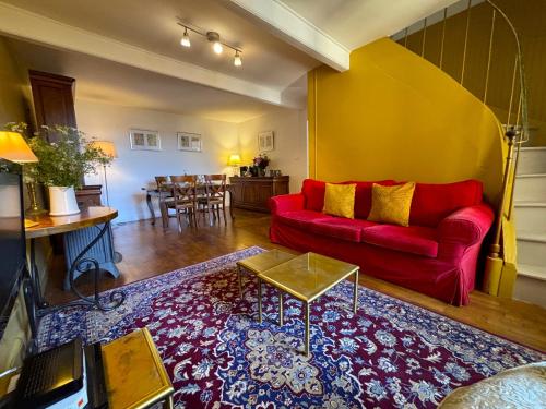 un salon avec un canapé rouge et une table dans l'établissement LE TERME maison en pierre dans village tous commerces au coeur du Périgord proche Sarlat et rivière Dordogne, à Saint-Cyprien