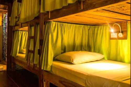 a bunk bed in a wooden room with a white pillow at Eco Hostal Yuluka in El Zaino