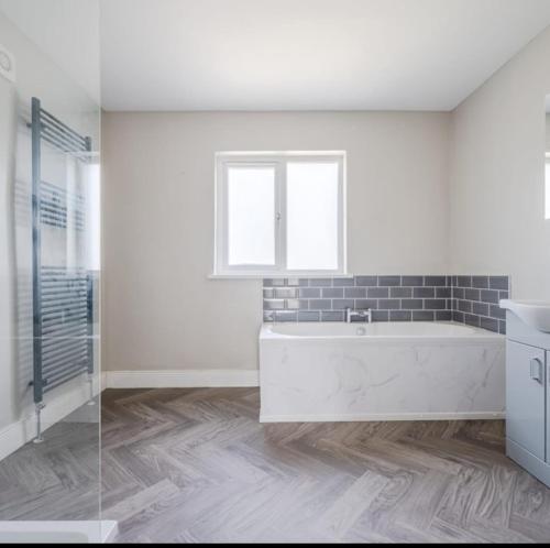 a white bathroom with a tub and a window at Fully refurbished house Belfast in Belfast
