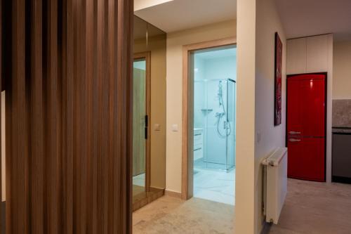 a hallway with a red door and a bathroom at MAROVA LUXURY APARTAMENT Caraiman VIEW in Buşteni
