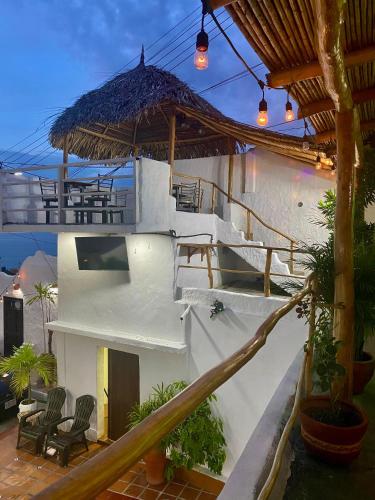 a white house with a patio with chairs and a umbrella at Posada Restaurant La Guaricha in Catia La Mar