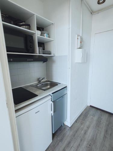 une petite cuisine avec un évier et un micro-ondes dans l'établissement Studio charmant au calme proche centre et plage, à Arcachon