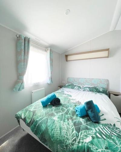 a bedroom with a bed with blue pillows on it at Ocean Breeze-Haven Perran Sands Holiday Park in Perranporth