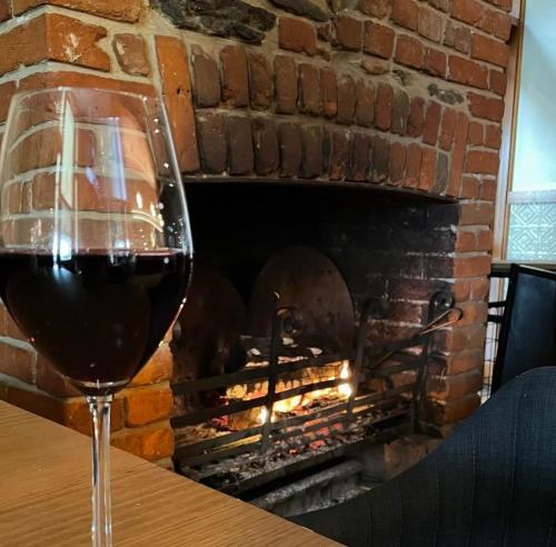 a glass of wine sitting on a table in front of a fireplace at Victoria Hotel Strathalbyn in Strathalbyn