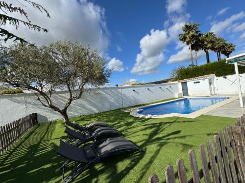 a group of chairs sitting next to a swimming pool at Villa Armonía in Arcos de la Frontera