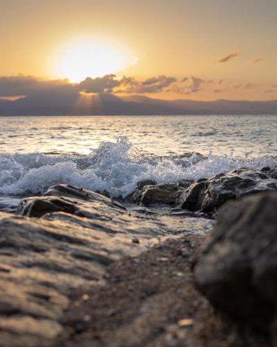 a sunset over the ocean with rocks in the water at Aegean Feelings in Piso Livadi