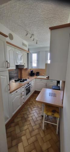 une cuisine avec des armoires blanches et une table en bois dans l'établissement Central & calme, vivez Troyes!, à Troyes