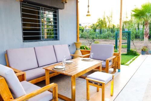 a patio with a couch and a table and chairs at Al Nakheel - Ferme Spacieuse avec Grande Piscine Privée et Espace Vert in Kenitra