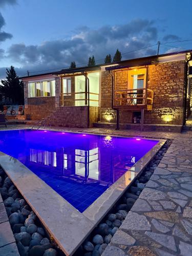 a swimming pool in front of a house at night at Mimani Stone House Roshnik in Roshnik