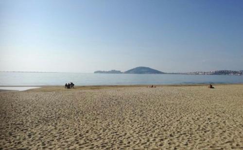 a group of people sitting on a beach near the water at Villa Agavi in Formia