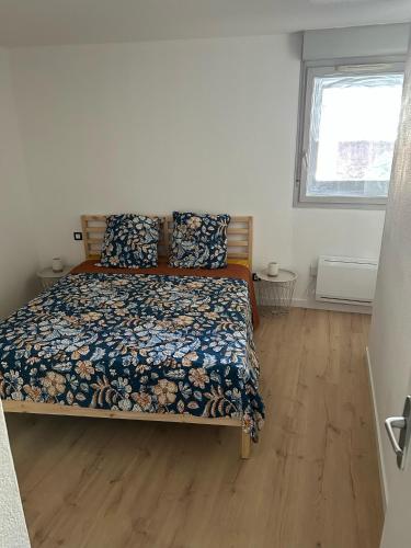une chambre avec un lit avec un couvre-lit fleuri dans l'établissement Appartement centre ville avec place de parking privée et balcon, à Montauban