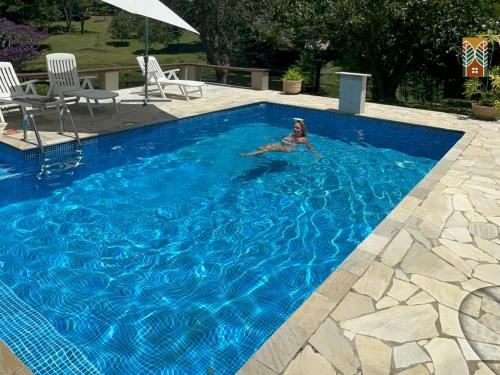 a woman is swimming in a blue swimming pool at Chales Vinhas da Harmonia l Pousada em Cunha SP in Cunha