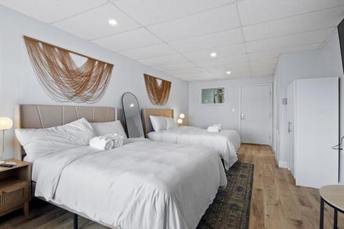 two beds in a room with white walls and wooden floors at Showboat Hotel in Himrod
