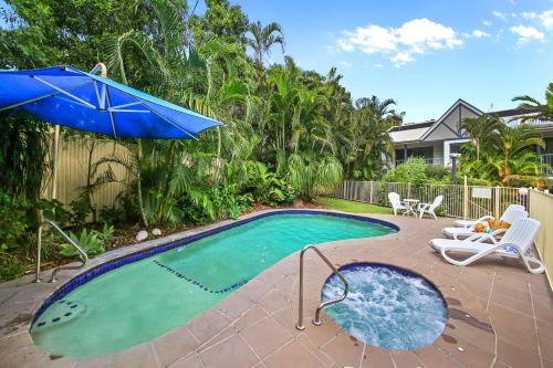 a swimming pool with an umbrella and a table and chairs at Chez Noosa Holiday Apartments in Sunshine Beach