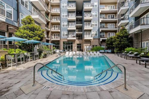 an outdoor swimming pool with chairs and a building at Modern 2BD - 5 Min DT, Gym, Parking, W-D - Sleeps 12 in Charlotte