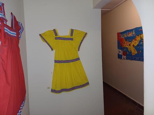 a yellow dress hanging on a wall next to two red dresses at BlueRock Hostal in David