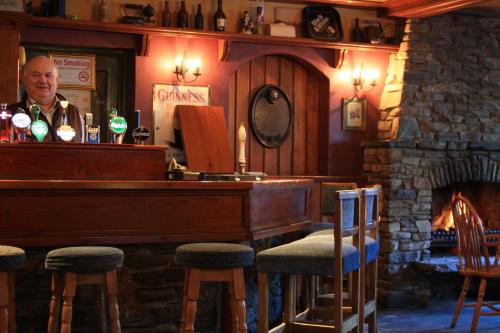 a man standing behind a bar with a piano at White Sands Hotel in Ballyheigue