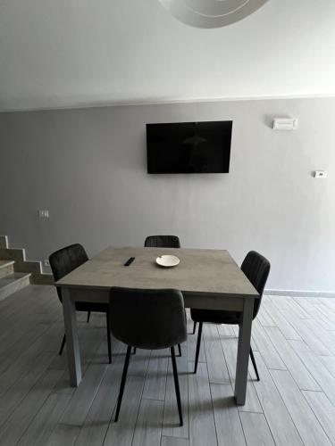 a dining room table with chairs and a television on a wall at Casa di Chiara in SantʼAgapito
