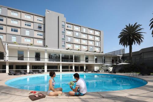 a man and woman sitting next to a swimming pool at Casa Andina Select Chiclayo in Chiclayo