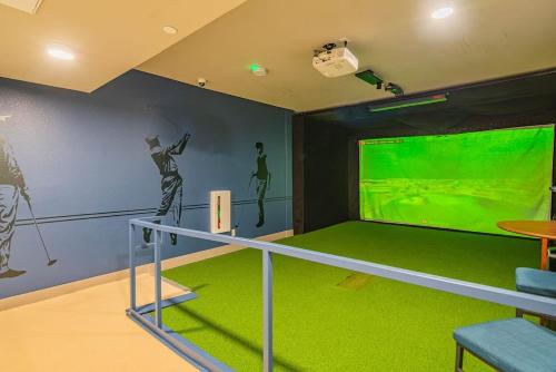 a room with a golf simulator with a green screen at Peaceful 1BR Kierland Common, TPC Golf, Pool, Gym, W-D in Scottsdale