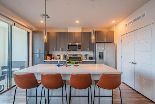 a kitchen with a large white island with orange chairs at Peaceful 1BR Kierland Common, TPC Golf, Pool, Gym, W-D in Scottsdale