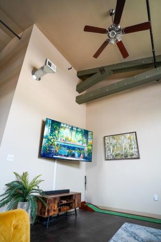 a living room with a ceiling fan and a flat screen tv at Industrial Escape in Lawrence