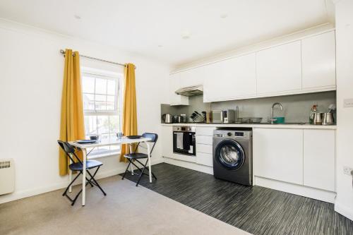 a kitchen with a table and a washing machine at Stunning 2-BR Home Gravesend Town Centre, Kent in Gravesend